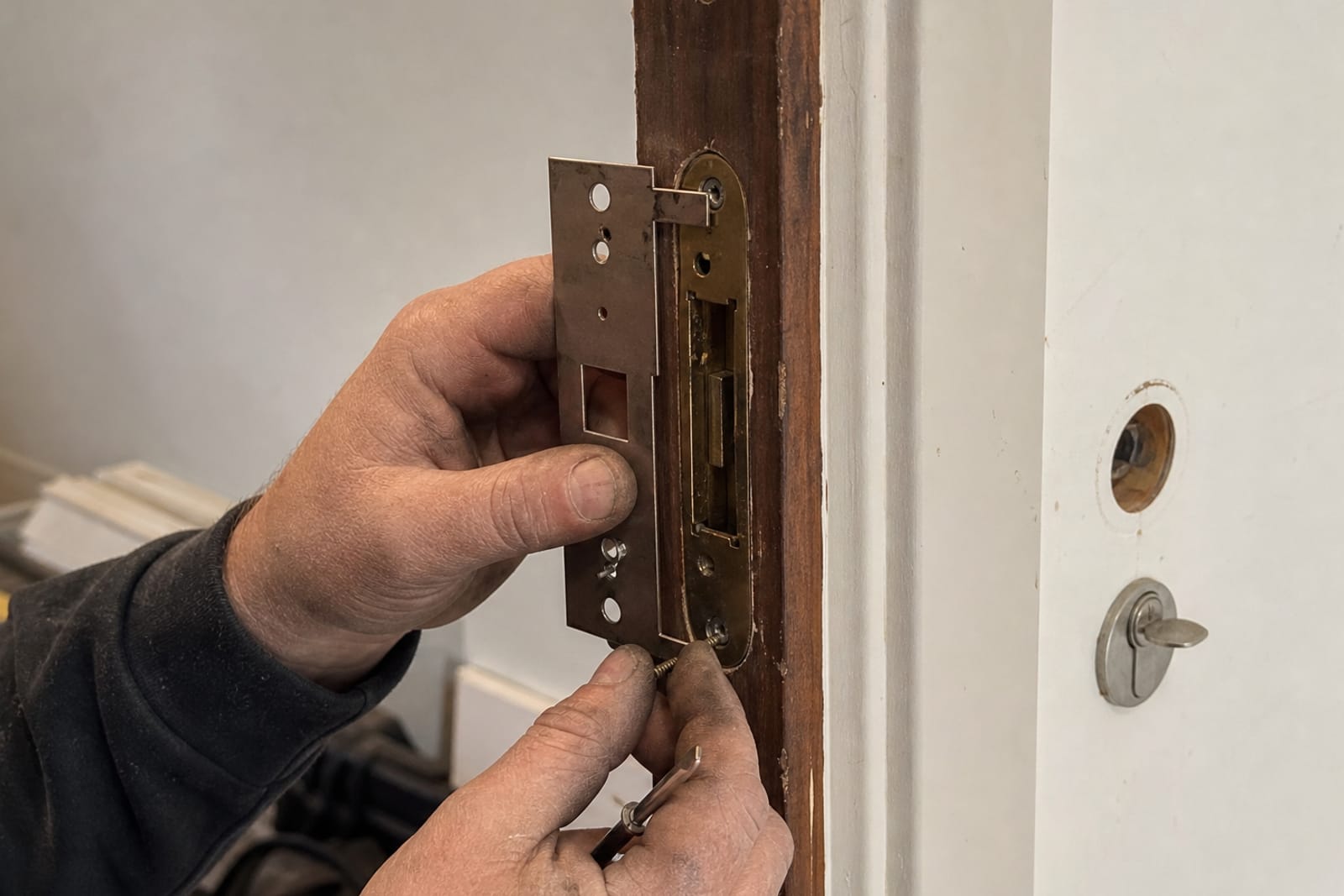 mains remplaçant une têtière de serrure
